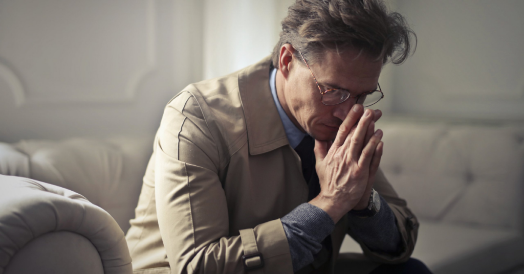 Frustrated middle-aged man sitting on couch, stressed about job hunting and career decisions