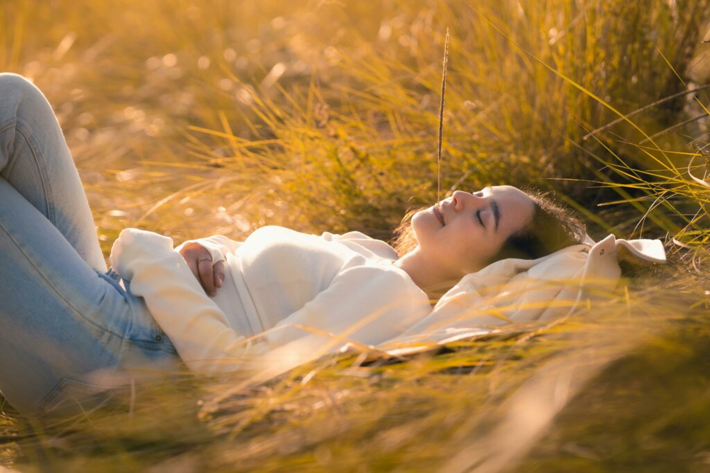 pexels-photo-29469337-29469337 | simon-walton.com A serene scene of a woman resting in a sunlit golden field, exuding tranquility.