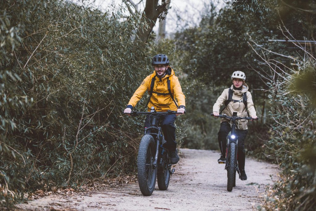 Couple enjoys cycling through a forest trail, embracing outdoor adventure and fitness.
