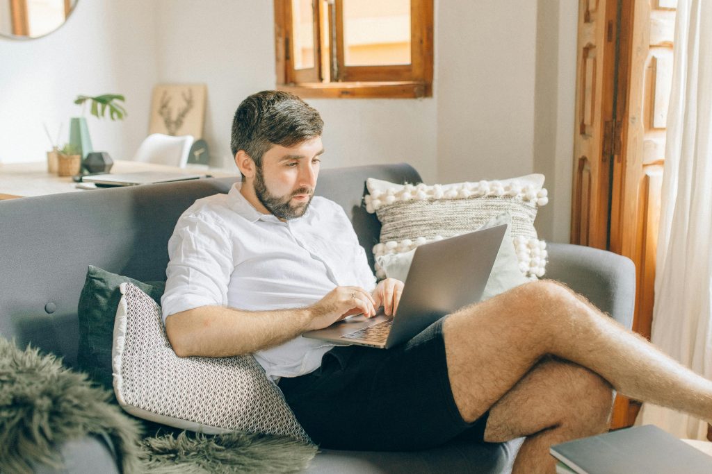 Middle-aged man working from home on his sofa—barefoot, focused, and clearly over corporate life.