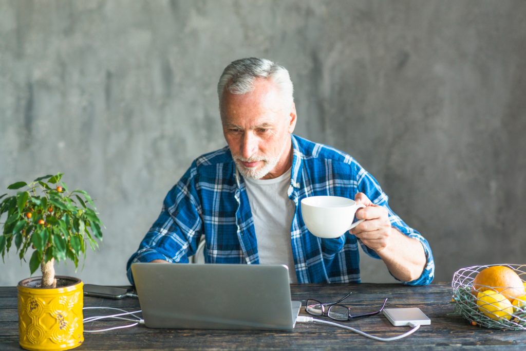 Middle-aged man working from home on laptop with coffee, exploring online business opportunities